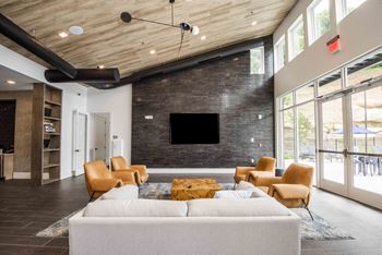A modern living room with a white couch and a flat screen TV mounted on a brick wall.